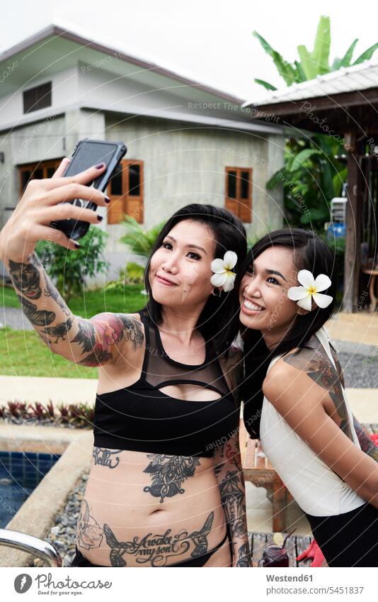Two happy women taking a selfies at swimming pool pools swimming pools Selfie Selfies happiness female friends woman females mate friendship Adults grown-ups