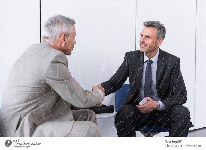 Business partners having a meeting, shaking hands office offices office room office rooms agreement Businessman Business man Businessmen Business men armchair