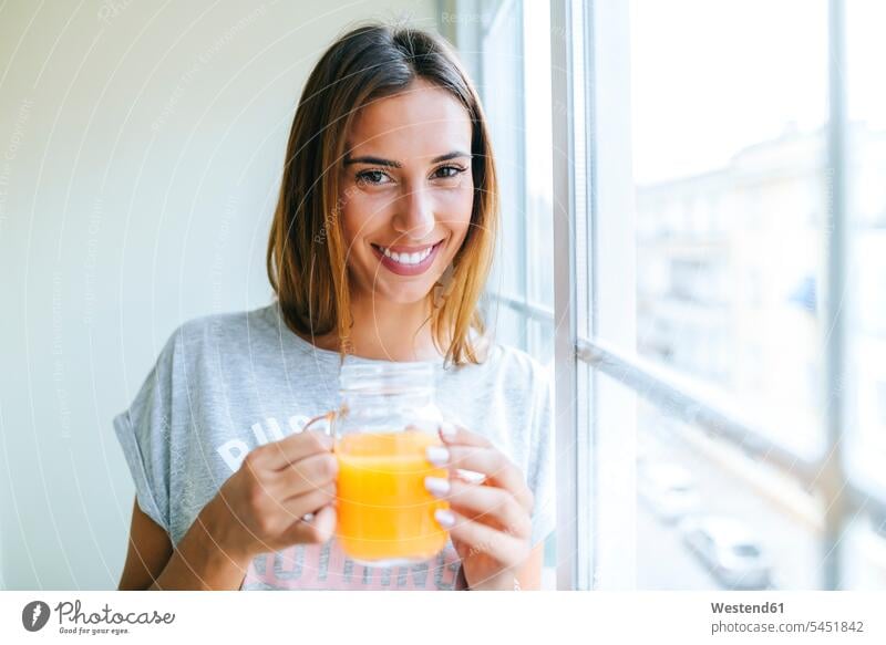 Portrait of smiling young woman with glass of orange juice portrait portraits females women Adults grown-ups grownups adult people persons human being humans