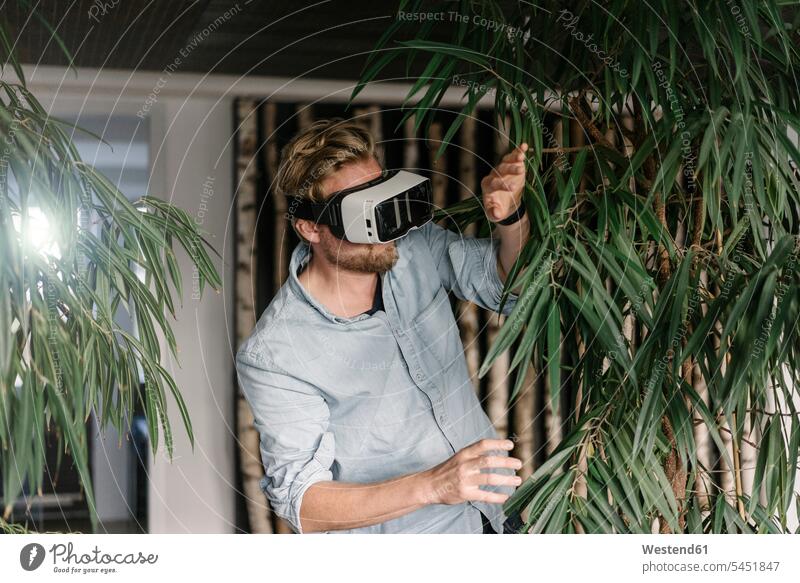 Man wearing VR glasses surrounded by plants virtual reality specs Eye Glasses spectacles Eyeglasses Foliage Plant Foliage Plants man men males house plant