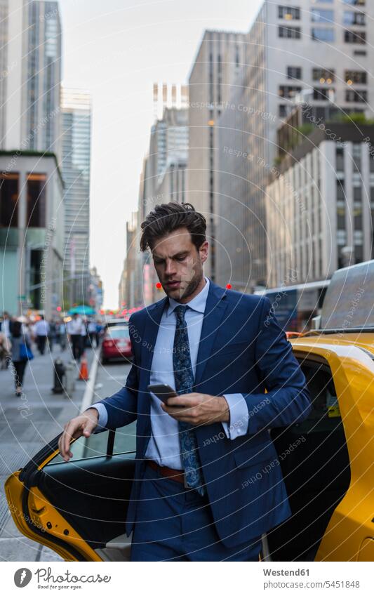 Businessman exiting yellow taxi in Manhattan attractive beautiful pretty good-looking Attractiveness Handsome mobile phone mobiles mobile phones Cellphone