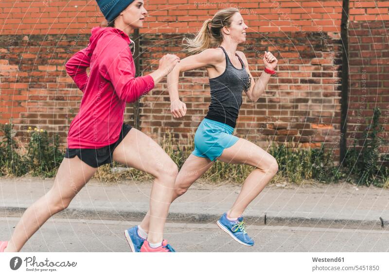 Two women running on the street Jogging woman females female friends fitness sport sports Adults grown-ups grownups adult people persons human being humans