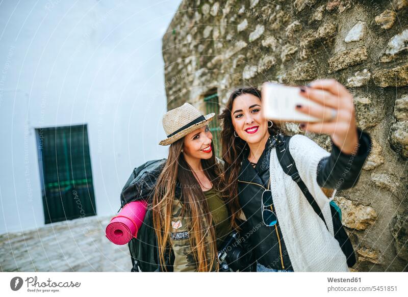 Two happy young women taking a selfie with a smart phone mobile phone mobiles mobile phones Cellphone cell phone cell phones Selfie Selfies photographing