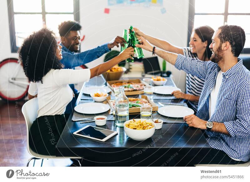 Group of friends having pizza and beer at home Table Tables Pizza Pizzas Beer Beers Ale eating toasting clinking cheers friendship Food foods food and drink