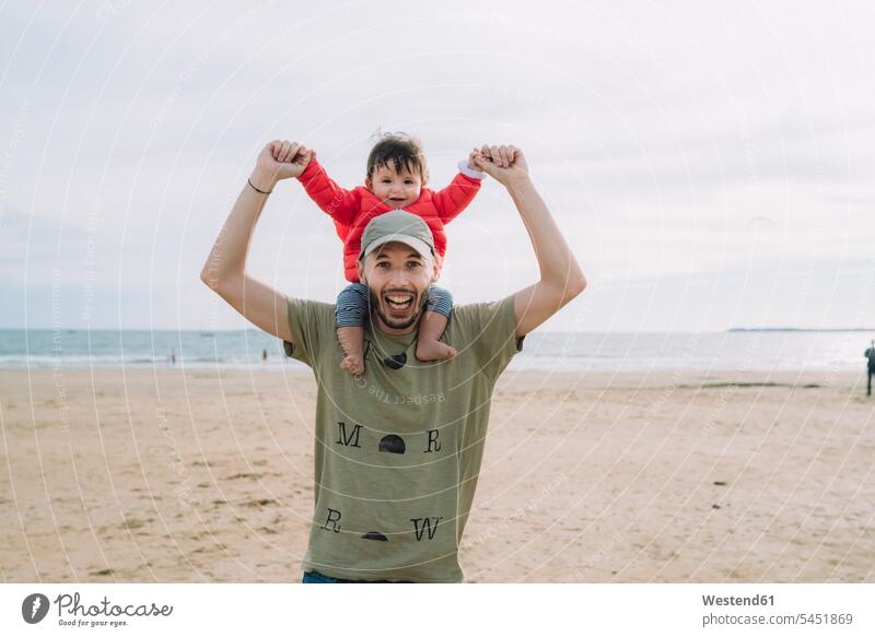Portrait of father carrying his little daughter on shoulders on the beach portrait portraits daughters beaches pa fathers daddy dads papa baby infants