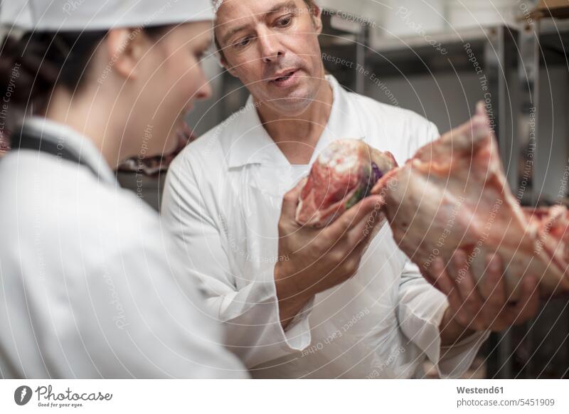 Man and woman with meat talking in storehouse of a butchery scrutiny scrutinizing charcuterie working At Work Food foods food and drink Nutrition Alimentation