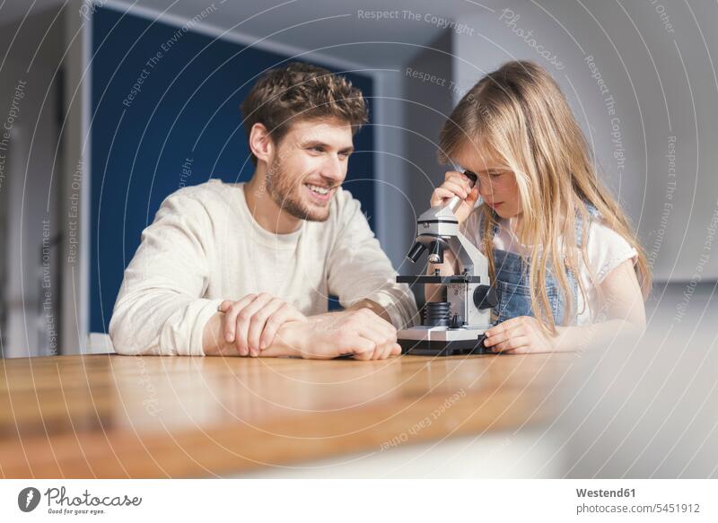 Father watching daughter use a microscope, smiling proudly Pride being proud playing girl females girls smile clever smart microscopes father pa fathers daddy