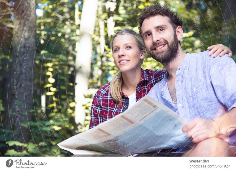 Smiling young couple with map in a forest smiling smile twosomes partnership couples maps woods forests people persons human being humans human beings
