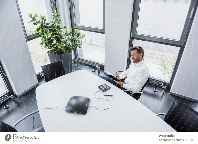 Businessman sitting at meeting table in his office offices office room office rooms Business man Businessmen Business men workplace work place place of work