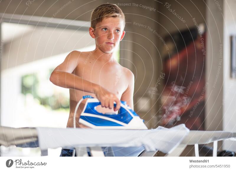 Shirtless teenage boy ironing cothes at home boys males chores child children kid kids people persons human being humans human beings waist up Waist-Up