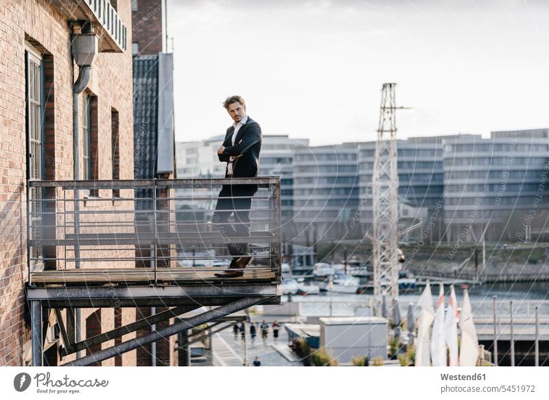 Pensive businessman standing on balcony balconies Businessman Business man Businessmen Business men independence independent business people businesspeople