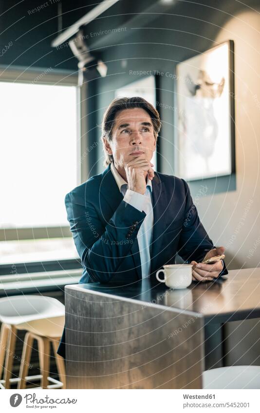 Businessman in cafeteria with cup of coffee thinking Coffee Cup Coffee Cups Business man Businessmen Business men business people businesspeople business world