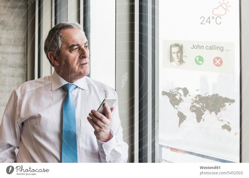 Businessman receiving a call on windowpane with world map in office world maps mobile phone mobiles mobile phones Cellphone cell phone cell phones Business man