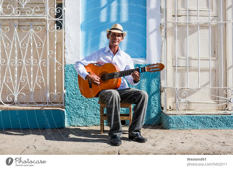 Cuba, Trinidad, portrait of man playing guitar on the street guitars street musician street musicians stringed instrument stringed instruments