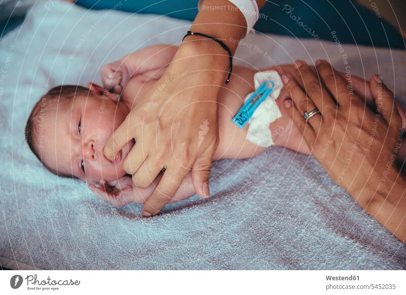 Newborn baby girl lying on towel sucking at mother's finger hand human hand hands human hands infants nurselings babies people persons human being humans