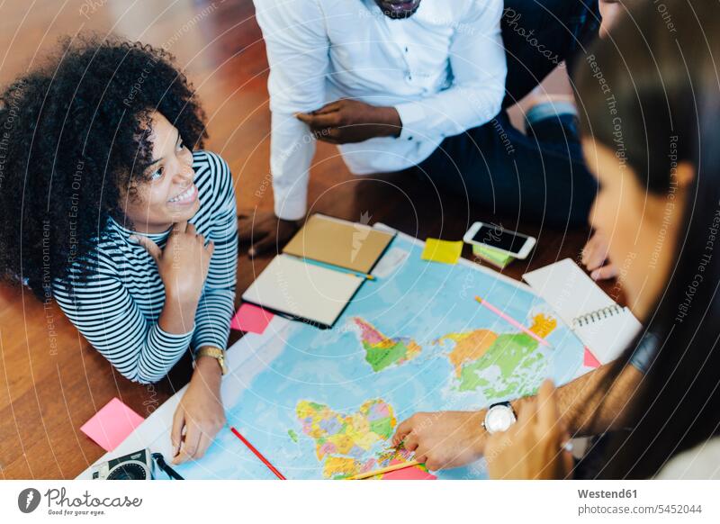 Group of friends planning vacation together map maps smiling smile travelling traveling friendship optimistic optimism note making a note note taking