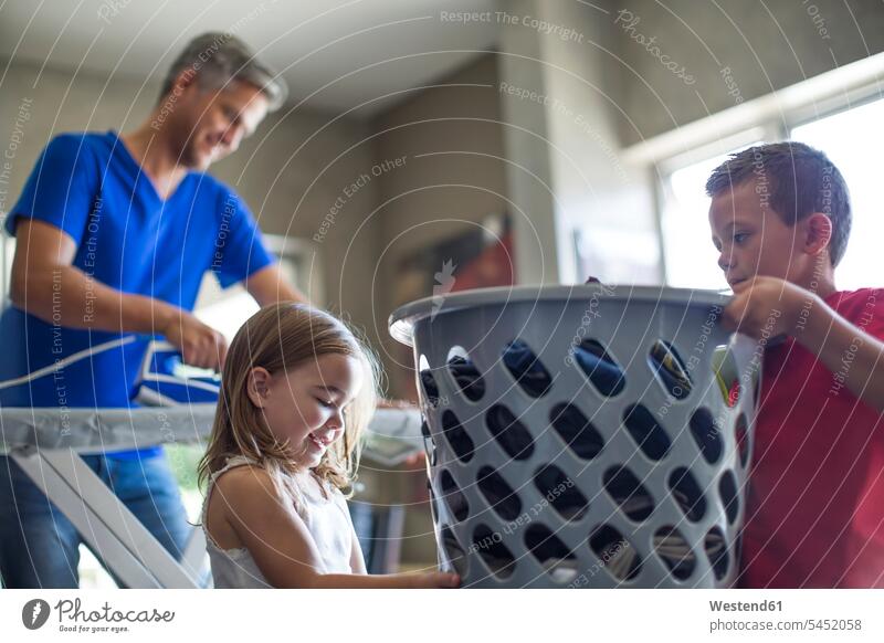 Two children helping father with chores carrying laundry basket Laundry home at home pa fathers daddy dads papa clothes basket assistance assisting Help parents