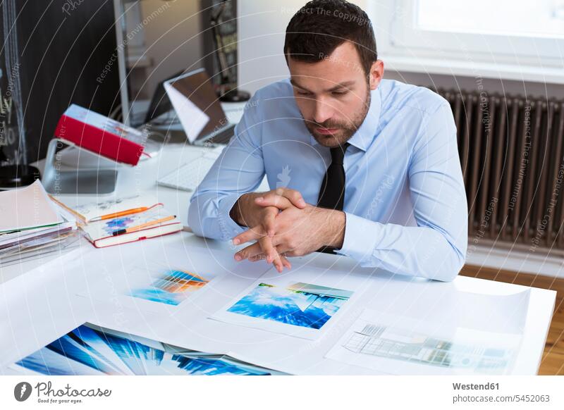 Businessman at desk in office looking at printouts working At Work Business man Businessmen Business men eyeing business people businesspeople business world