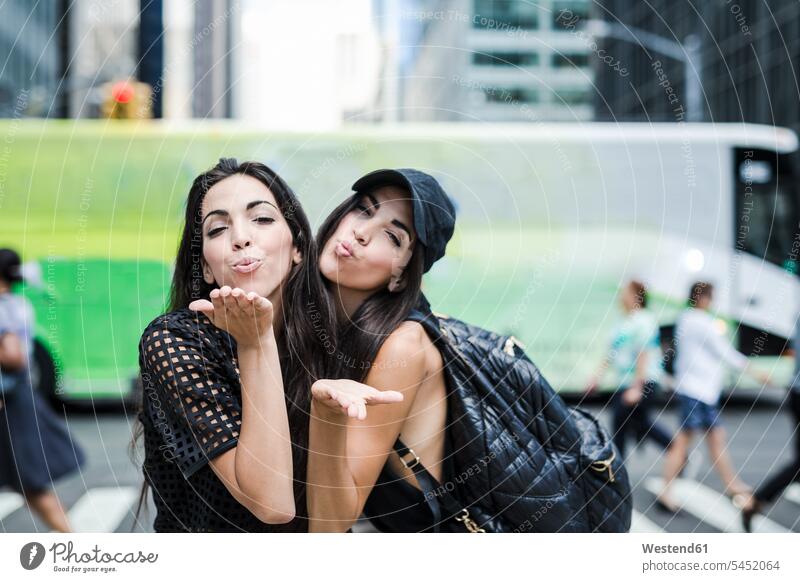 USA, New York City, two twin sisters blowing a kiss in Manhattan New York State female friends Fun having fun funny siblings brother and sister