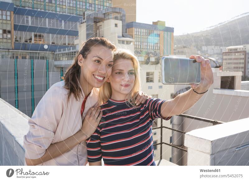 Friends taking selfies on a rooftop terrace roof terrace deck smiling smile photographing friends celebrating celebrate partying Selfie Selfies camera cameras