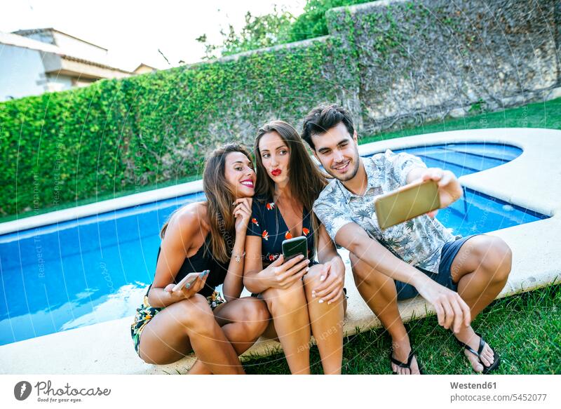 Friends taking a selfie at the poolside mobile phone mobiles mobile phones Cellphone cell phone cell phones smiling smile swimming pool swimming pools happiness