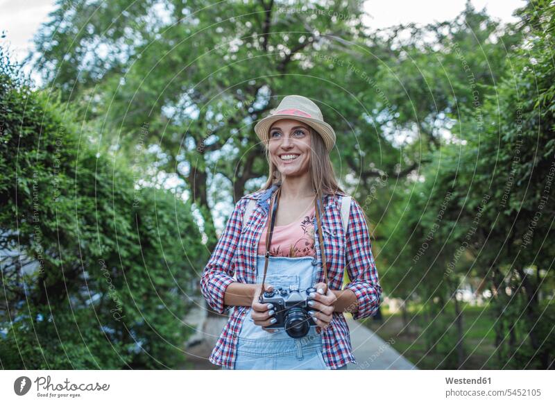 Smiling young woman with a camera in a park cameras smiling smile parks females women Adults grown-ups grownups adult people persons human being humans