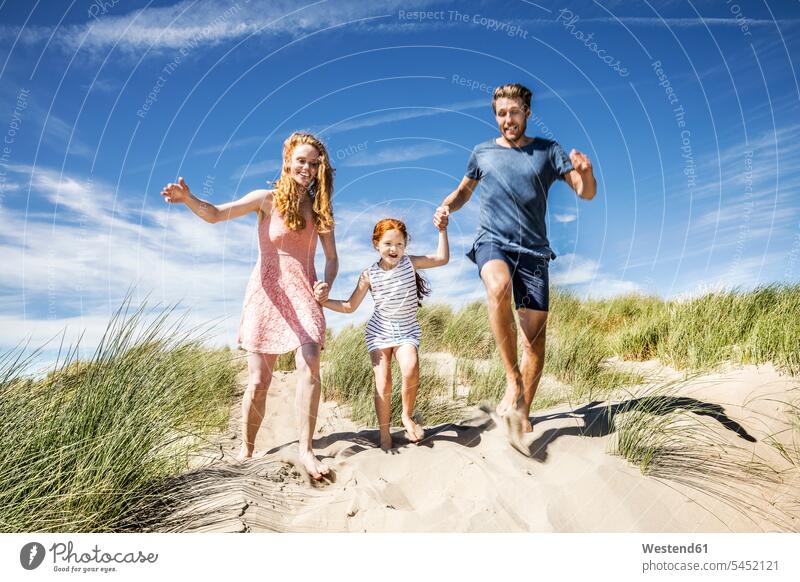 Netherlands, Zandvoort, happy family with daughter running in beach dunes happiness Fun having fun funny beaches families people persons human being humans