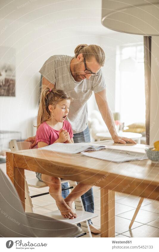 Father checking homework of his daughter daughters father pa fathers daddy dads papa Home work child children family families people persons human being humans