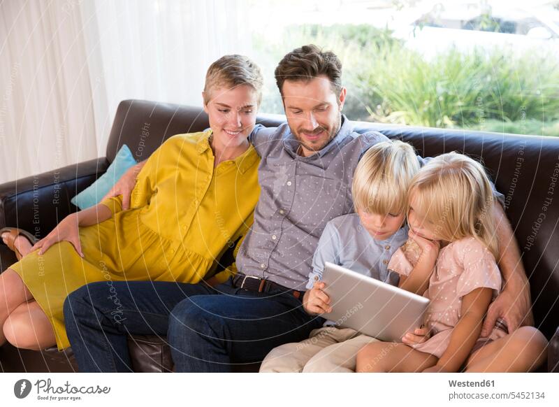 Family sitting on couch at home using tablet Seated digitizer Tablet Computer Tablet PC Tablet Computers iPad Digital Tablet digital tablets family families use