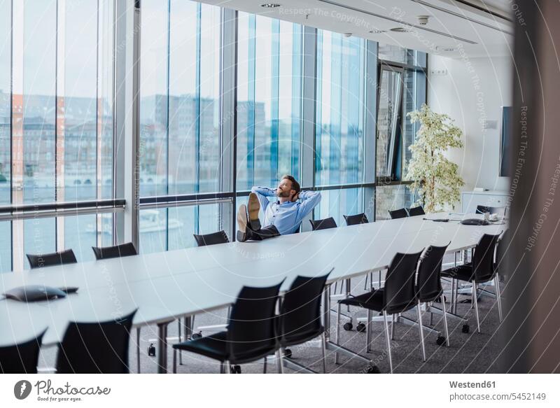 Germany, Berlin, businessman sitting in conference room with feet up looking out of the window Businessman Business man Businessmen Business men business people
