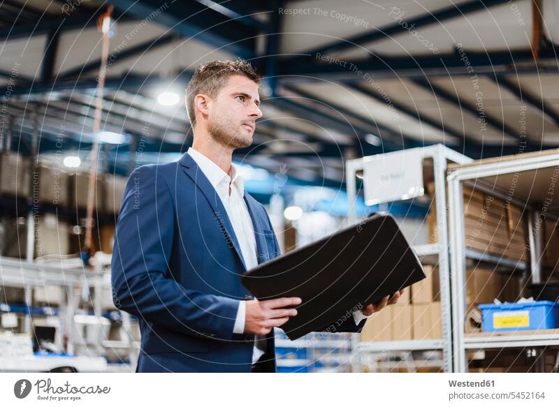 Portrait of a young manager in the shop floor, holding file standing inventory stocktaking stock control company firm document paper documents papers brown hair
