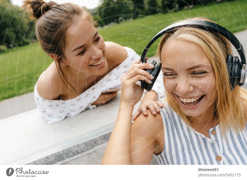 Two happy young women with headphones outdoors female friends headset happiness woman females sharing share mate friendship Adults grown-ups grownups adult