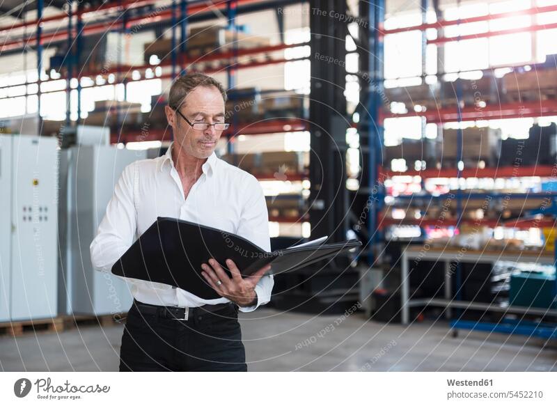 Man with documents on factory shop floor factories folder file folders portfolio portfolios files man males Adults grown-ups grownups adult people persons