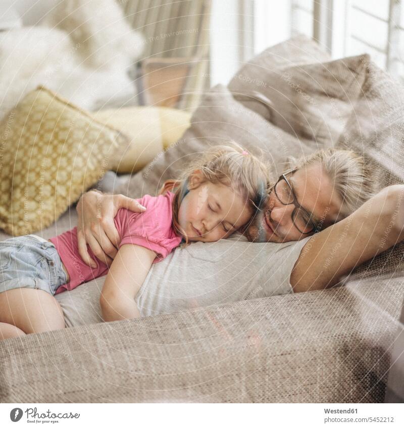 Father relaxing with daughter on sofa couch settee sofas couches settees lying laying down lie lying down happiness happy father pa fathers daddy dads papa