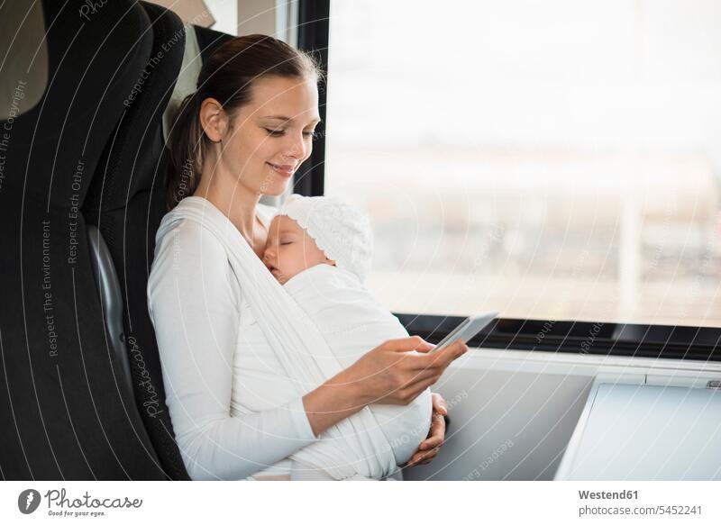 Mother with baby girl traveling by train looking on cell phone smiling smile travelling mother mommy mothers ma mummy mama infants nurselings babies window