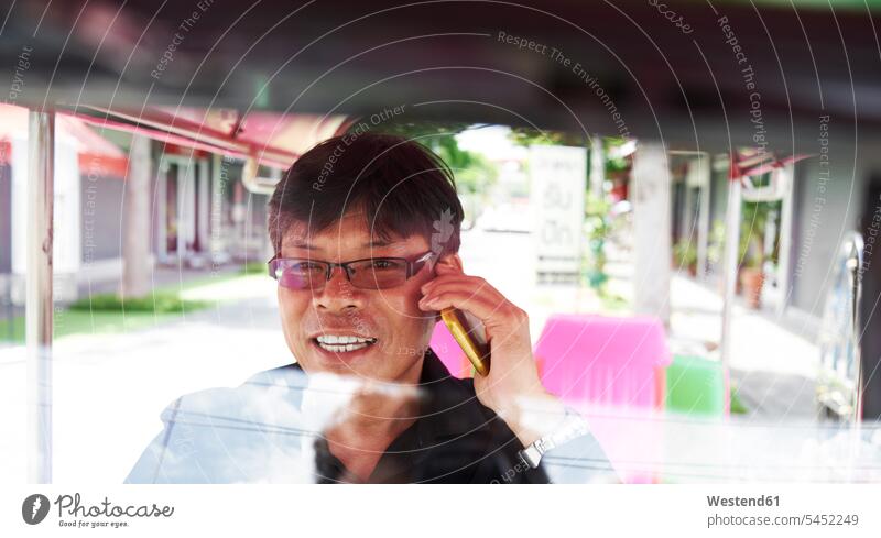 Thailand, Bangkok, tuk tuk driver talking on cell phone Smartphone iPhone Smartphones on the phone call telephoning On The Telephone calling conversations