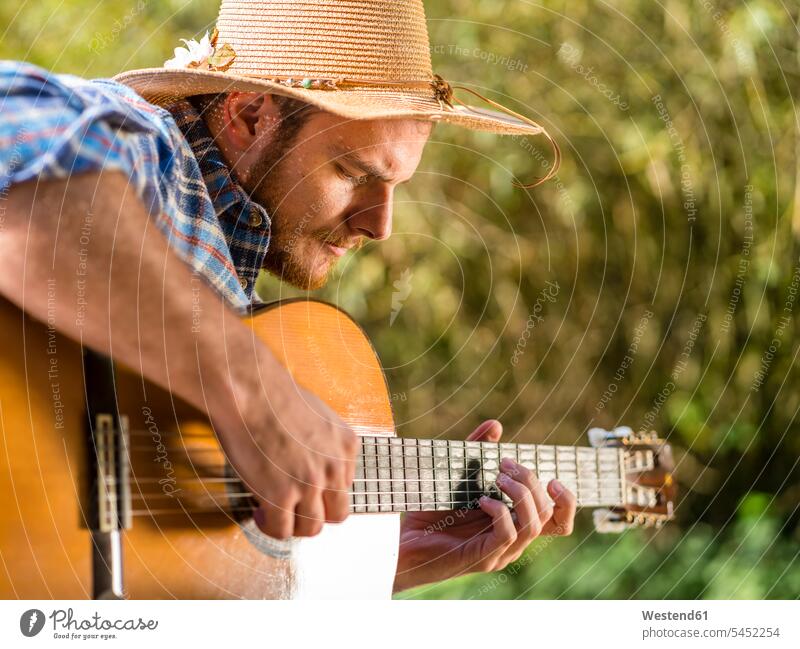 Man playing guitar in nature guitars men male adults man males natural world musician musicians guitarist guitarists making music playing music make music