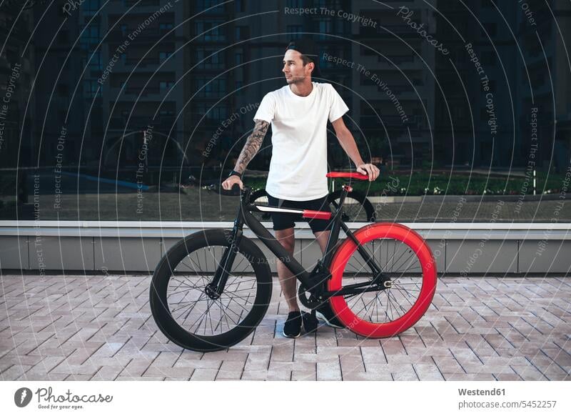 Young man with fixie bike in the city standing bicycle bikes bicycles men males Adults grown-ups grownups adult people persons human being humans human beings