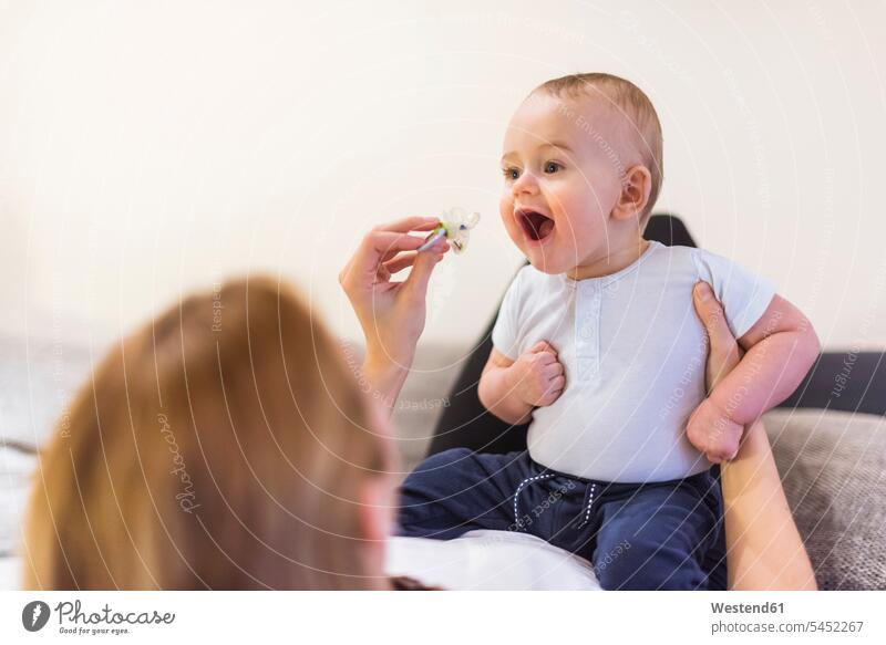 Mother and baby son playing with pacifier Pacifiers comforter soother infants nurselings babies mother mommy mothers ma mummy mama sons manchild manchildren