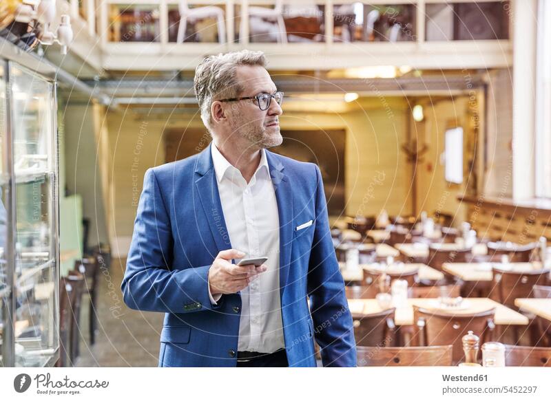 Mature businessman in cafe holding cell phone mobile phone mobiles mobile phones Cellphone cell phones Businessman Business man Businessmen Business men