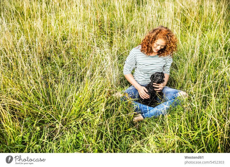 Young woman relaxing on a meadow with her dog dogs Canine females women meadows pets animal creatures animals Adults grown-ups grownups adult people persons