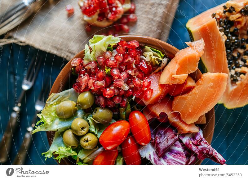 Close-up of papaya salad, pomegranate, lettuce, tomato, olives and endive in bowl vitamines still life still-lifes still lifes pomegranate seed