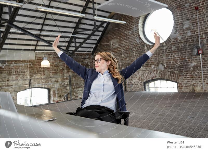 Businesswoman stretching at table in a loft businesswoman businesswomen business woman business women sitting Seated leaning back Reclining Recline