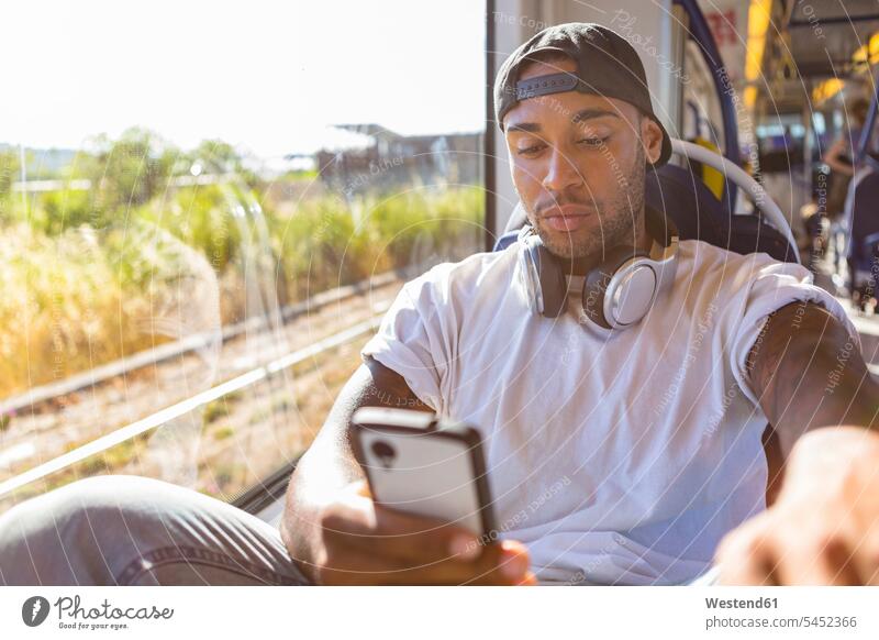 Portrait of young man in tramway looking at smartphone Smartphone iPhone Smartphones tramways streetcars trams men males mobile phone mobiles mobile phones