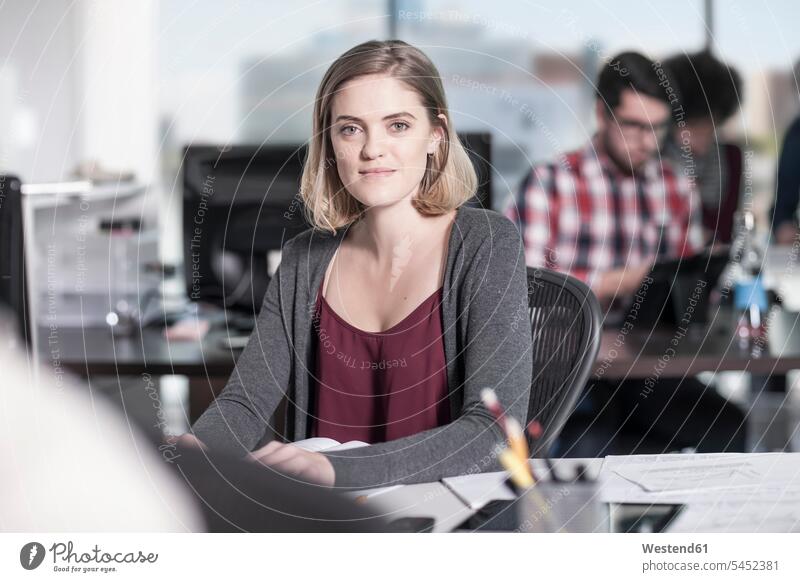 Portrait of smiling woman at desk in office portrait portraits smile working At Work offices office room office rooms workplace work place place of work