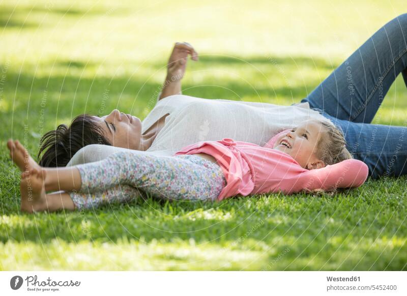Mother and daughter lying in grass smiling smile daughters happiness happy mother mommy mothers ma mummy mama meadow meadows relaxed relaxation laying down lie