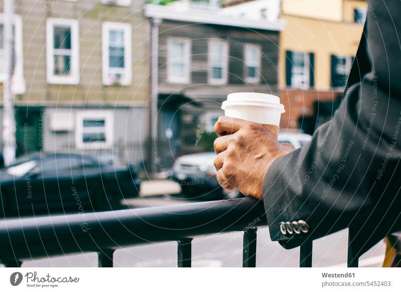 Hands of a man holding cup of coffee on railing Coffee hip trendy cool attitude composed coolness laid-back Brooklyn men males Drink beverages Drinks Beverage