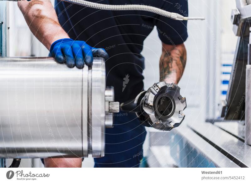 Close-up of man holding workpiece in industrial factory machine men males working At Work factories device devices Adults grown-ups grownups adult people