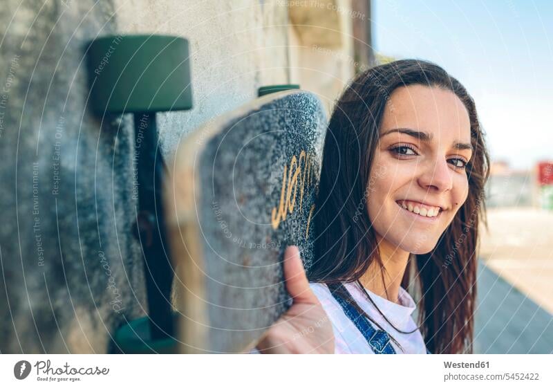 Portrait of smiling young woman with skateboard on her shoulders portrait portraits piggyback piggy-back pickaback Piggybacking Piggy Back Skate Board