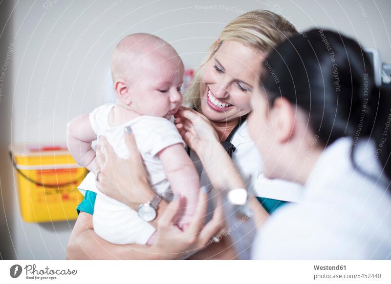 Female pedeatrician holding baby at examination babies infants pediatrician paediatricians people persons human being humans human beings doctor physicians